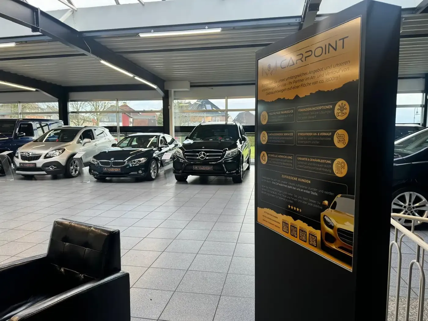 Aufsteller in der Halle mit den Leistungen von PR Carpoint, daneben Fahrzeuge
