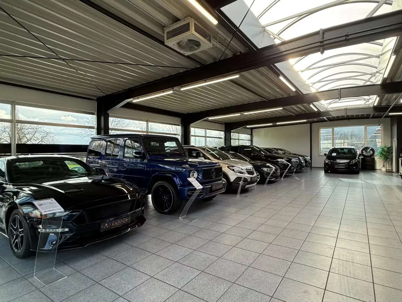 Ausstellungshalle mit Mercedes-AMG G 63, Mustang und Kombis