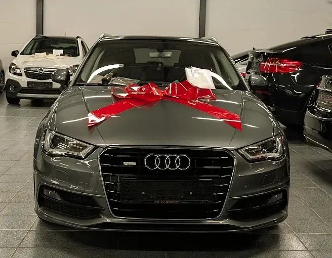 Audi A3 mit roter Schleife auf der Haube, bereit zur Übergabe in der Halle von PR Carpoint