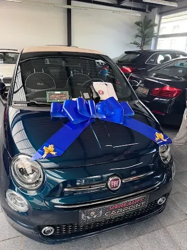 Fiat 500 mit blauer Schleife auf der Haube in der Halle