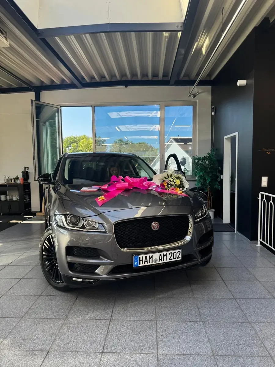 Jaguar F-Pace mit pinker Schleife und Blumenstrauß am Übergabetag